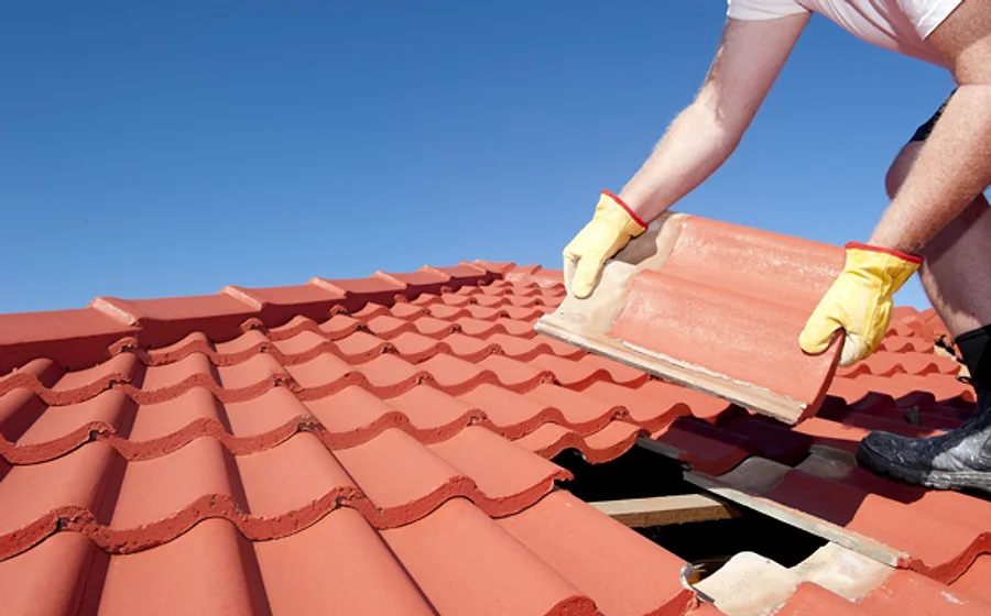 A roofer fitting a replacement roof tile